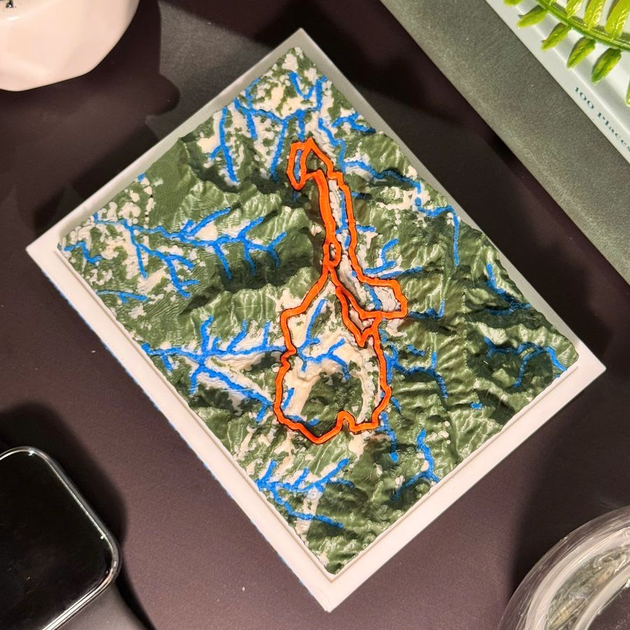 The printed VMM 100 Miles tile seen from above: forest green relief, blue rivers, the orange route.